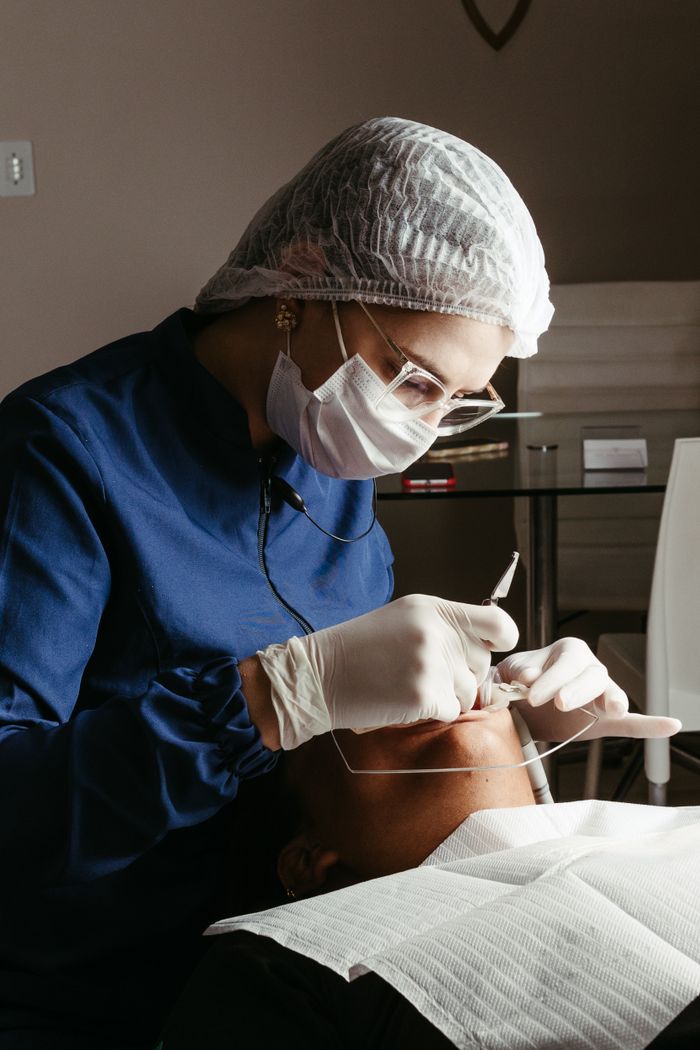 services-01 A dentist in a medical clinic performing a procedure on a patient, focusing on dental care and hygiene.
