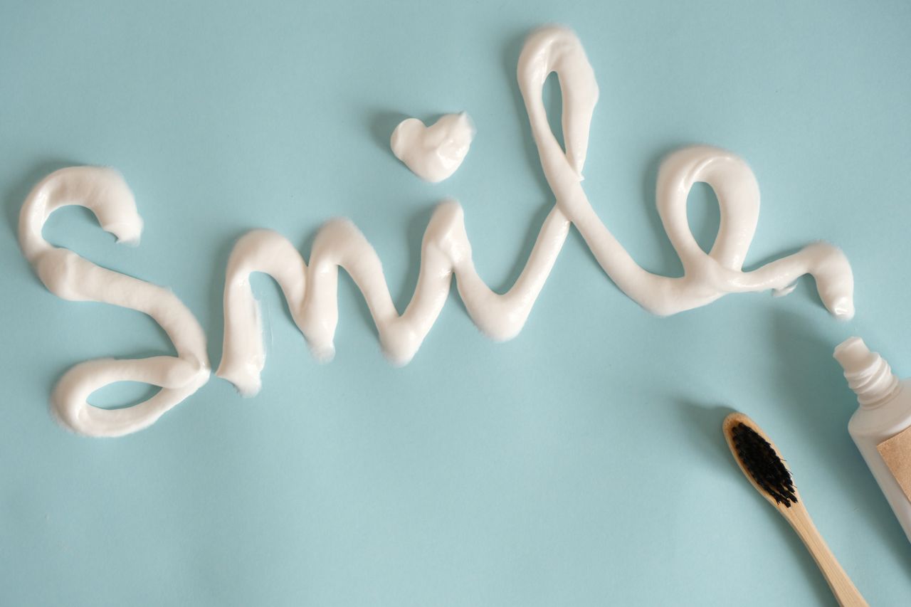 hero-services Toothpaste spelling 'Smile' on turquoise surface with toothbrush.
